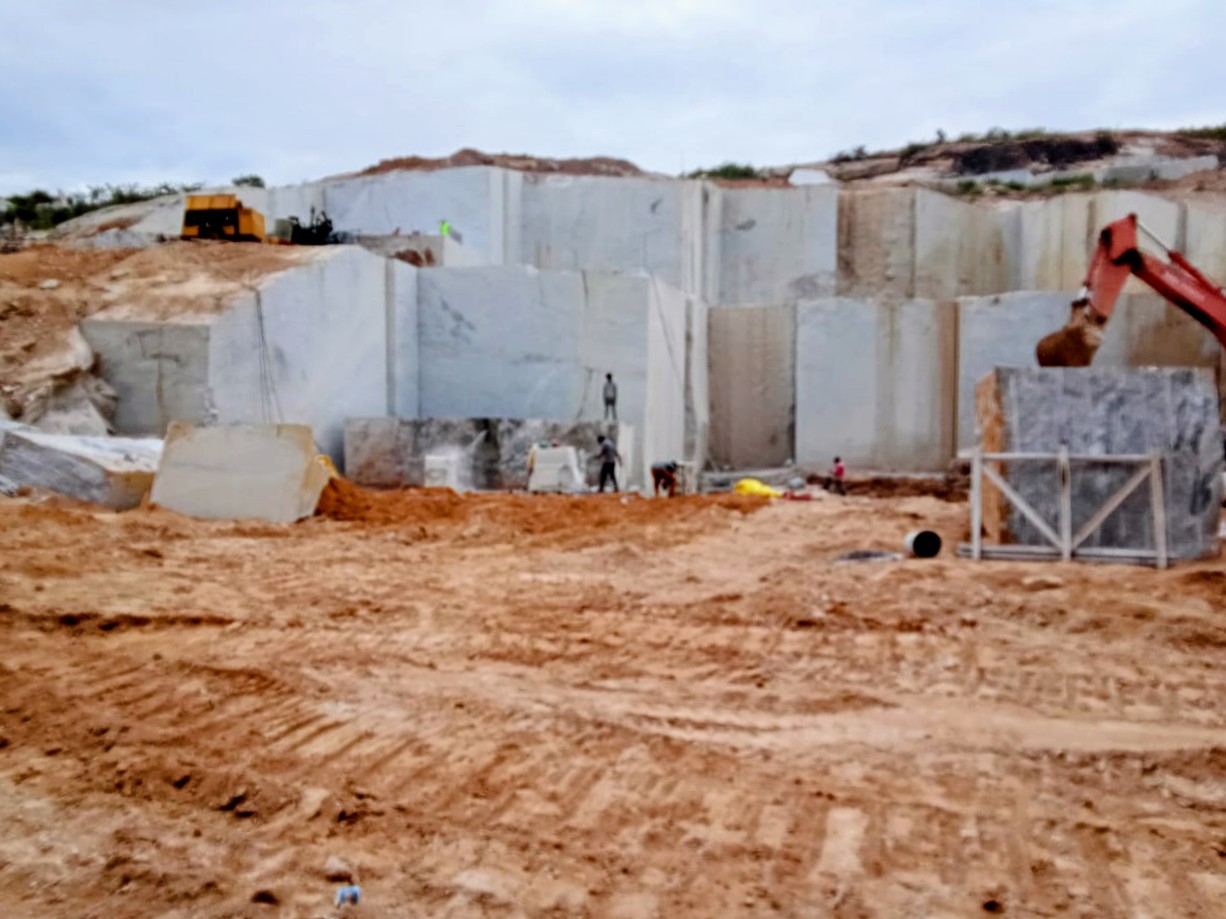 White granite quarry with excavator and dimensional blocks ready for dressing